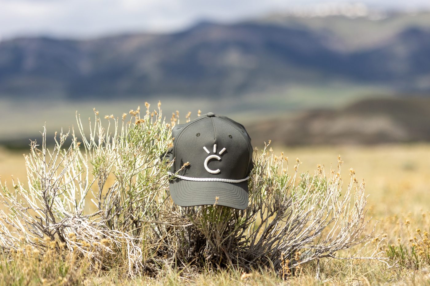 The Sagebrush Cap, a dark olive Cavvy rope hat with a white logo and rope